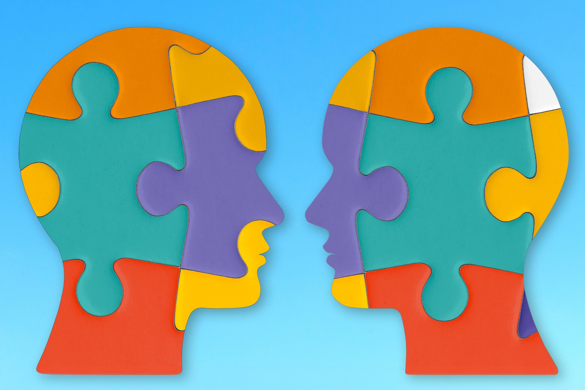 Two Colorful Puzzle Piece Heads Facing Each Other on Blue Background