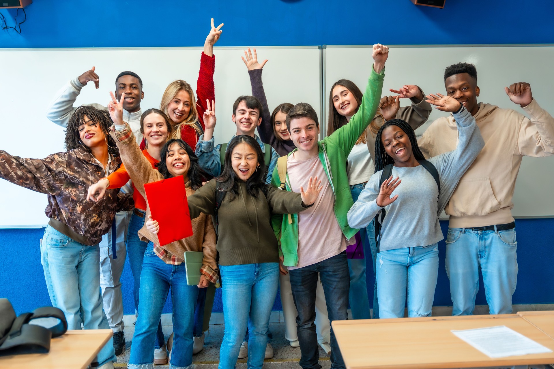 Cheerful university students celebrating inside classroom